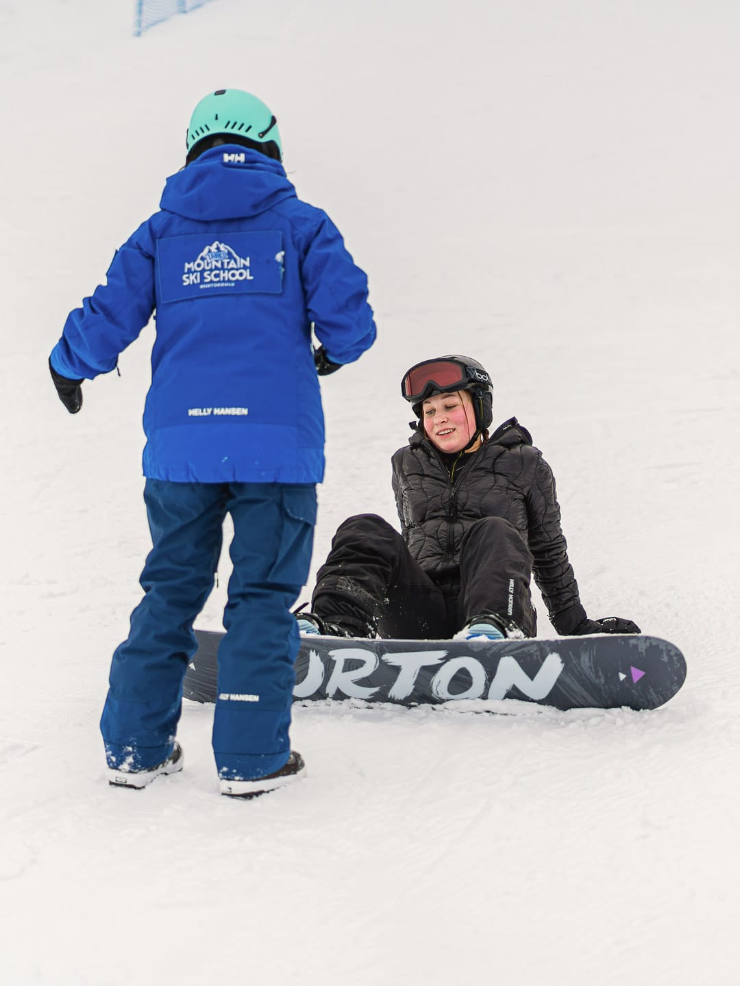 Hiihtokoulun opettaja neuvoo lautailijaa.