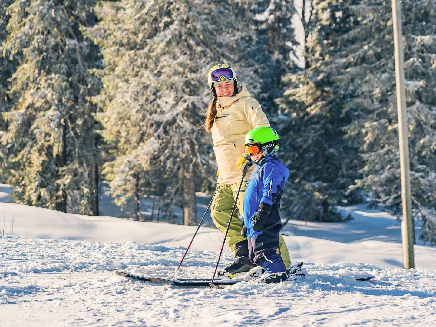 Lapsi ja aikuinen seisoo sukset jalassa.