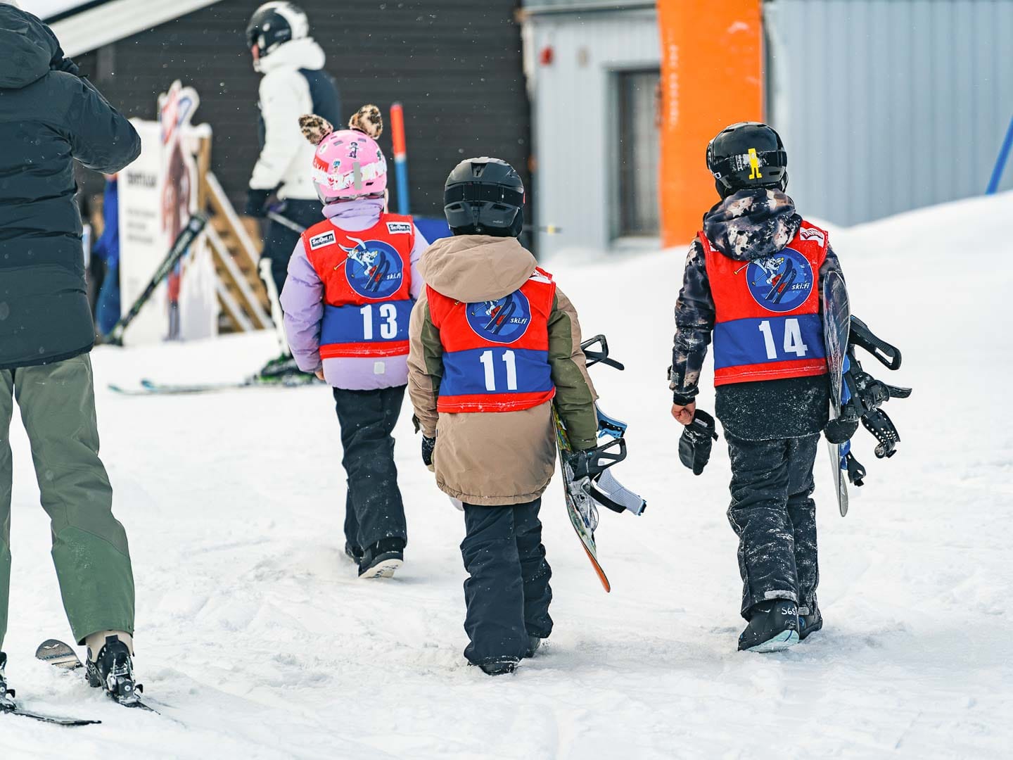Lapset kantavat lumilautoja.